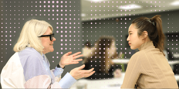 A photograph showing two people in conversation, with a pattern of pink dots overlaid.