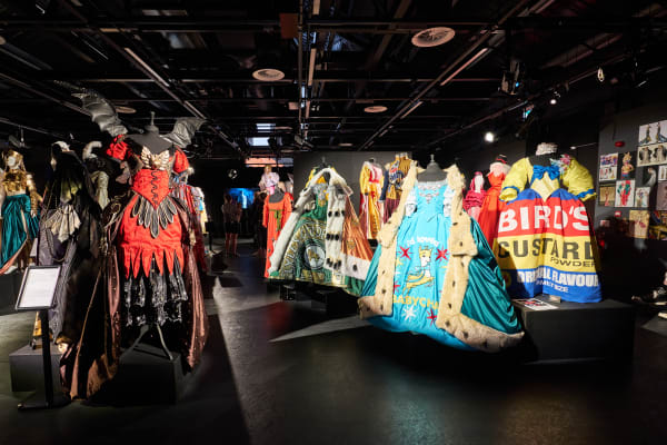 A vibrant graduate showcase display featuring a variety of ornate theatrical costumes on mannequins.
