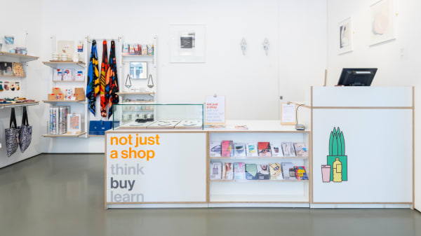 A brightly lit store featuring a sign on the counter that reads 