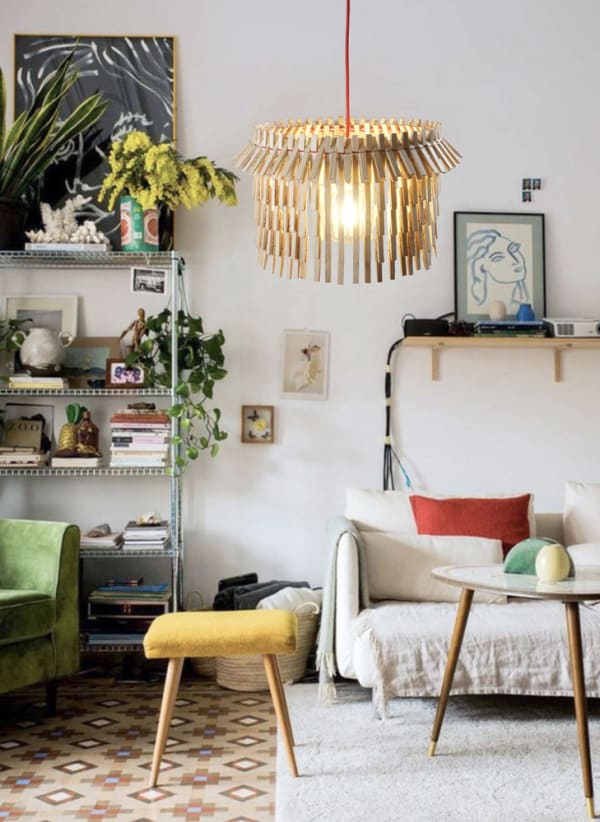 Image of a fully furnished living space showing a light and wooden lampshade, sofa, stool, coffee table and bookshelves