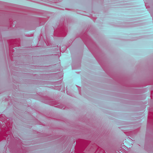 hands moulding a hand built clay vase in a pottery studio