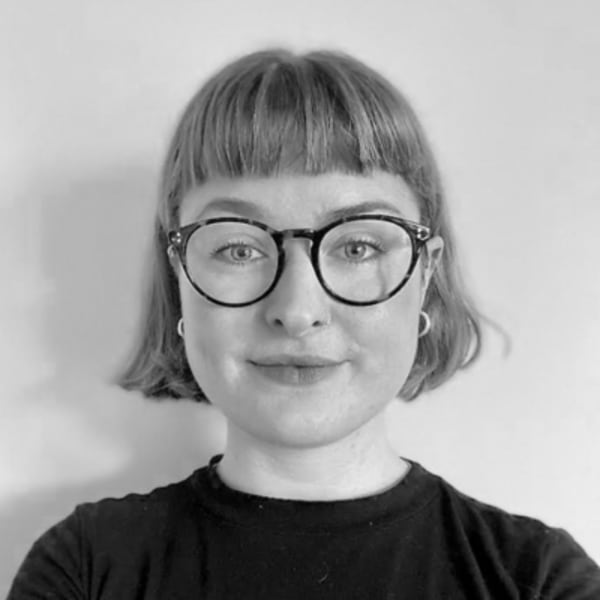 Lucy Graham, a woman with short blonde hair, a black tshirt and brown round glasses