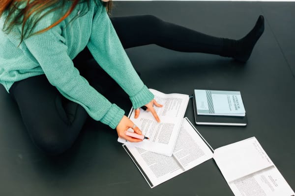 Student on the floor, writing on notebooks