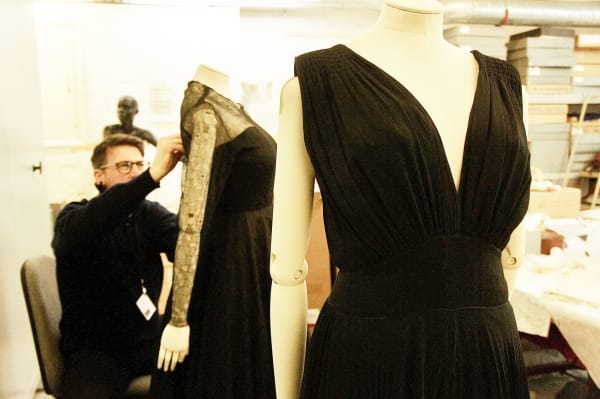 Curator dressing 2 mannequins with evening dress