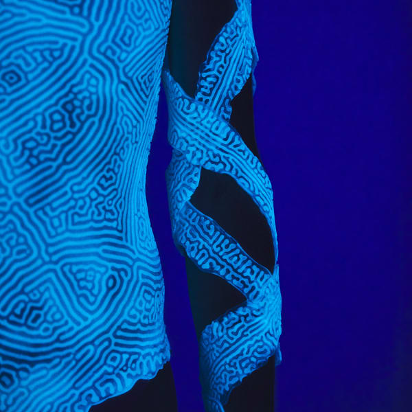 Bioluminescent fabric wrapped in two intertwining strands down a model's arm  