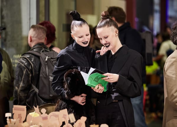 A smiling pair of visitors are sharing a moment while exploring the exhibition catalogue