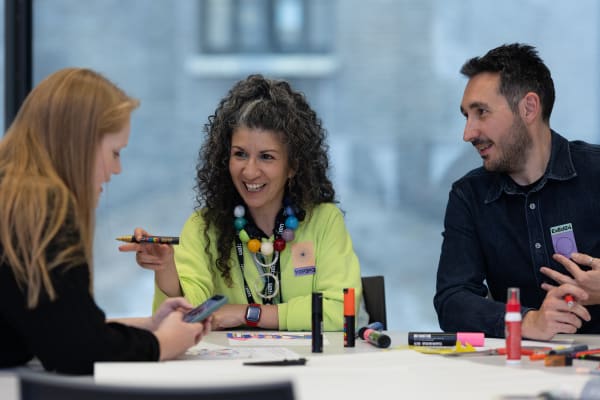 Three people chat around a table
