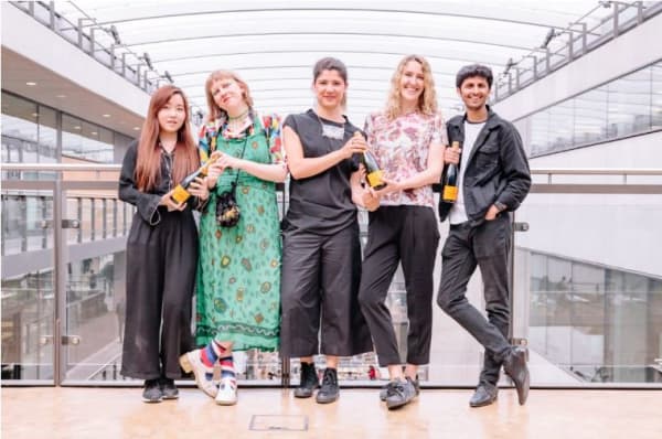 Four people stood together holding bottles of wine