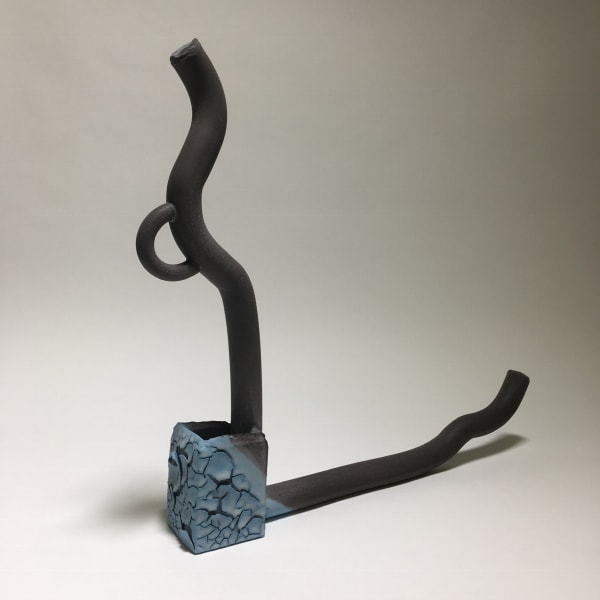 Photograph of a ceramic sculpture of a jug fragmented, with two armatures coming out at right angles to each other