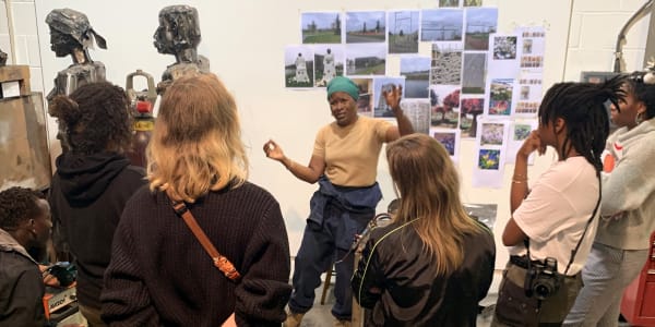 A group of students inside the artist Sokari Douglas Camp's studio which is full of photographs and sculptures