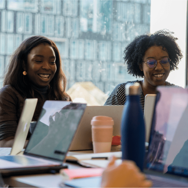 women in front of laptops smiling