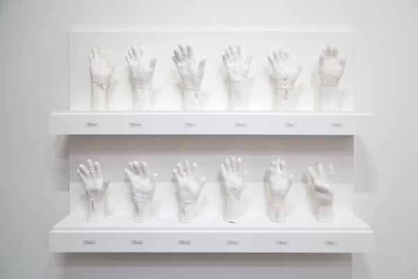 An all-white sculpture of upright hands with different finger postions