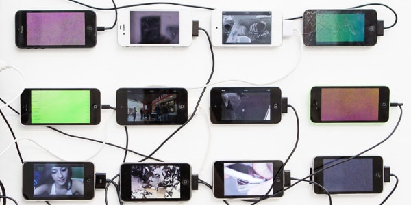 Iphones laid out side by side with chargers plugged in