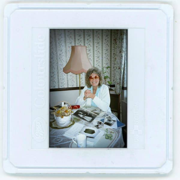 A-Polaroid-picture-of-a-lady-wearing-red-glasses-sitting-at-a-table-with-magazines.jpg