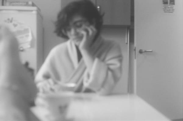 Black and white photograph of a girl sitting at a kitchen table by Monica Santos - BA Fine Art.
