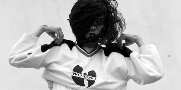 A girl putting on a jumper with 'Wu-Tang- logo