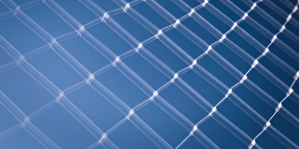 Close up photograph of a chain link fence with blue sky in the background