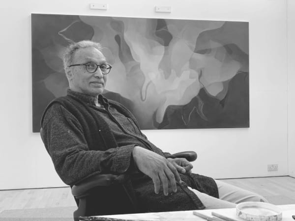 Black and white portrait of Gavin Jantjes sitting comfortably in a desk chair