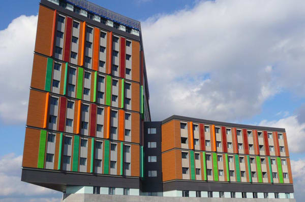 Exterior of Emily Bowes Court, showing a colourful tall building in front of blue sky.