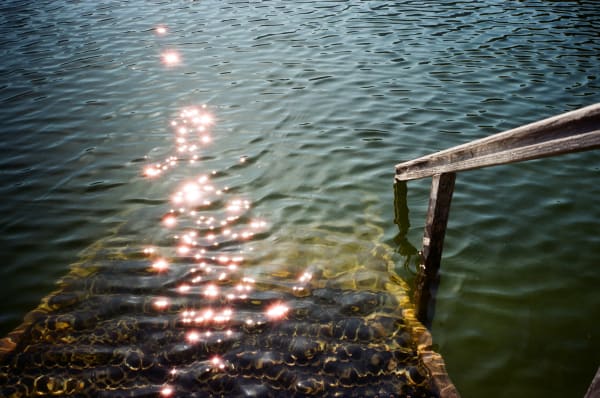 Photograph of steps down into the water in a lake taken on a sunny day with the sun glistening on the water by Pippa Healy - MA Fine Art: Printmaking