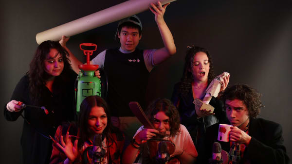 Group shot of actors with various props in their hands.