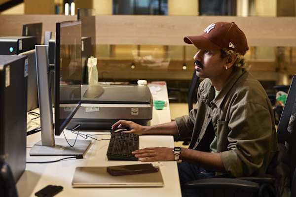 Person wearing a cap working at a computer desk