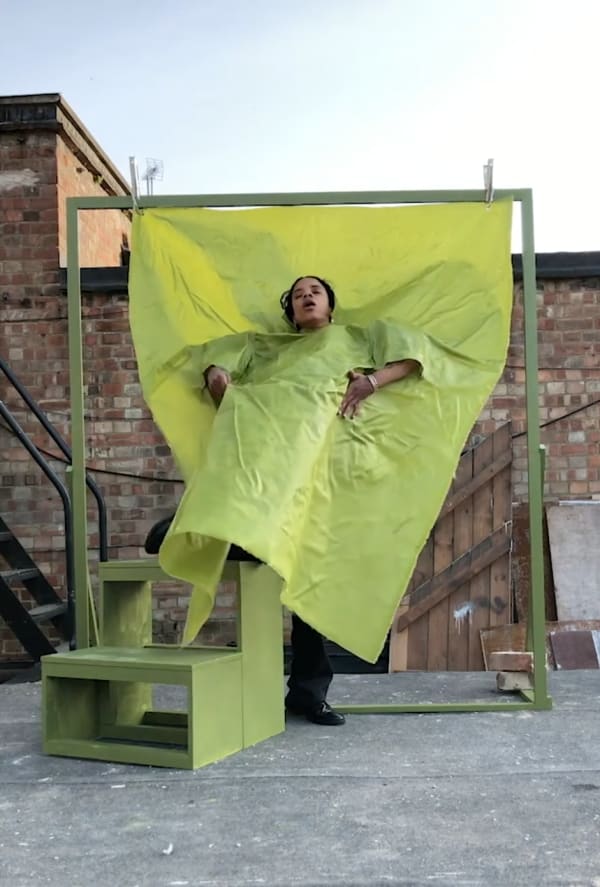 Woman enveloped in green fabric hanging from frame