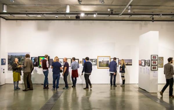 Photo of a group of people in the distance looking at art on a white wall