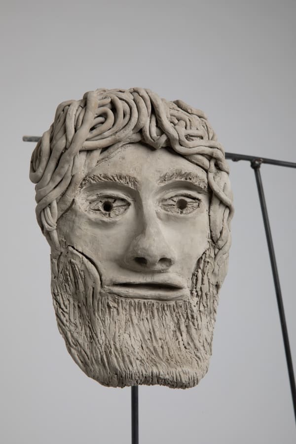 A ceramic sculpture of a man's face with a beard 