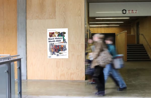 Campaign poster featuring collage artwork posted on wood wall in busy hallway