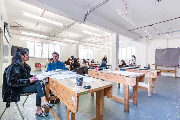 Students working at a desk inside Central Saint Martins' Archway campus
