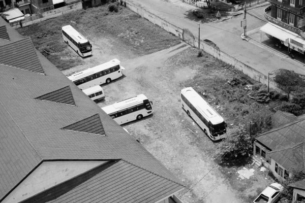 Black and white photograph showing a birds-eye-view of coaches in an urban setting.