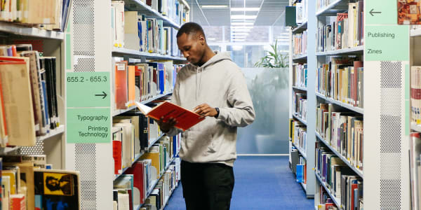 Young man reading a book in the library