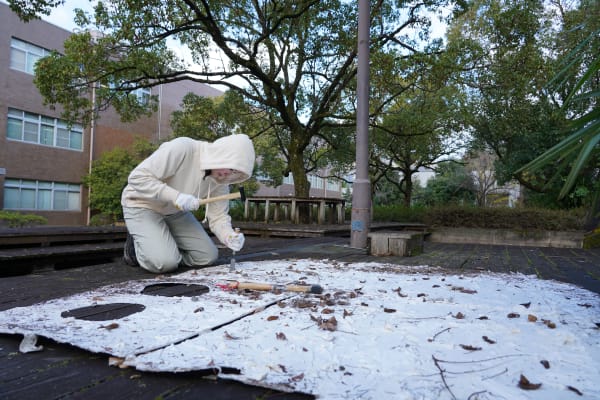 A person in white coveralls working outdoors on top of a building or structure