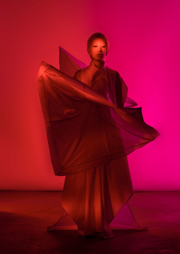 Figure wearing white garments lit in red