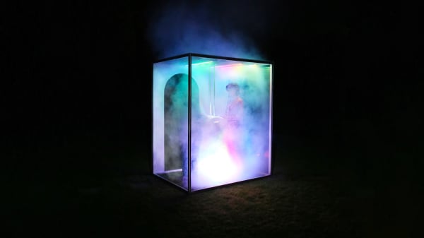 Cube exhibition space with luminescent colours and smoke.