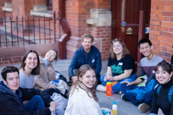 Group of students sitting on the ground and smiling to the camera