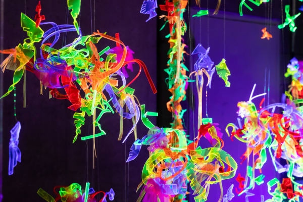 Brightly coloured neon mobiles against a dark background