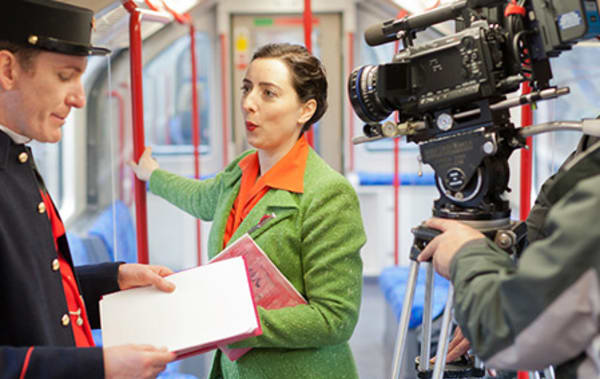 A woman being filmed on a tube carriage