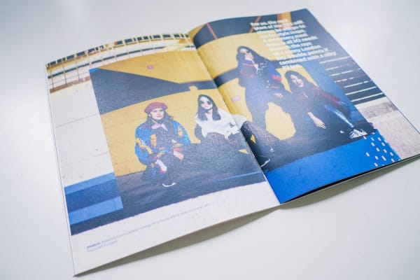 Double-spread in a magazine. Showing four people posing in front of a yellow wall.