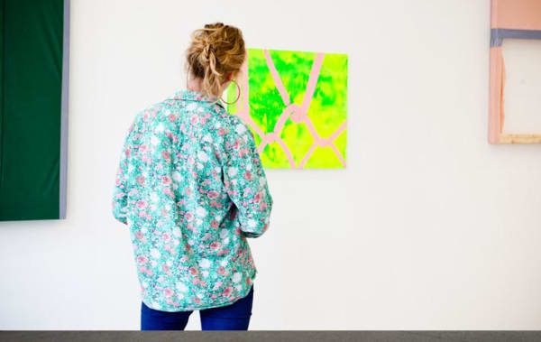 Girl in floral shirt looking at yellow picture on the wall