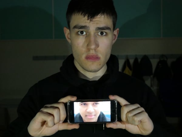 image of a student holding phone with an image of a different person displayed on phone