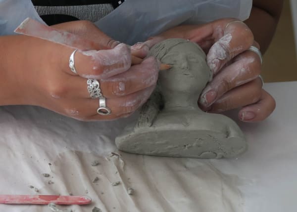 Hands sculpting a clay head