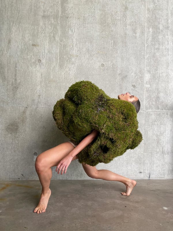 Figure bend back wearing large mossy garment