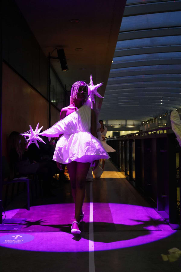 Figure wearing wight garments  walking down pink lit pathway