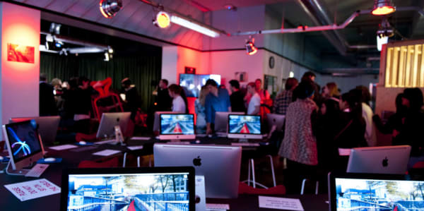 People at an event in a gallery featuring various computer screens