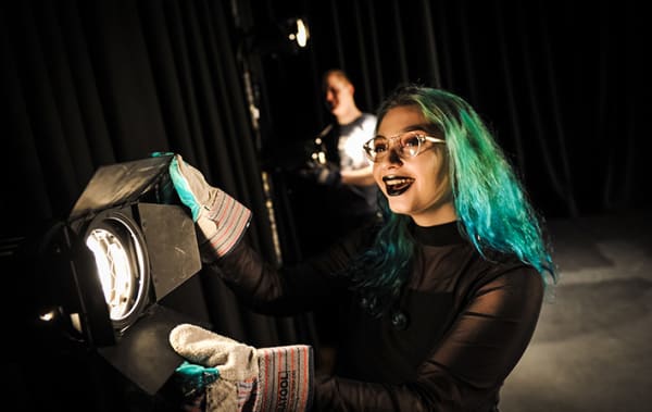 Green-haired girl operating a stage light