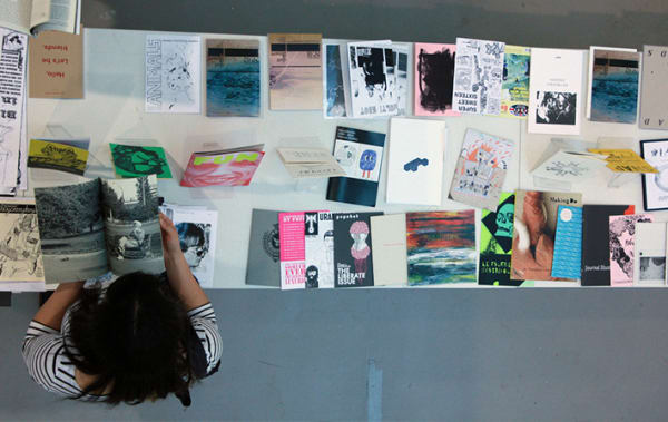 Aerial view of a woman standing over a table of papers and art work laid out