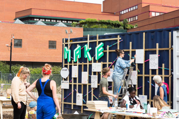 Exterior of Make space with people on ladders and view of British Library