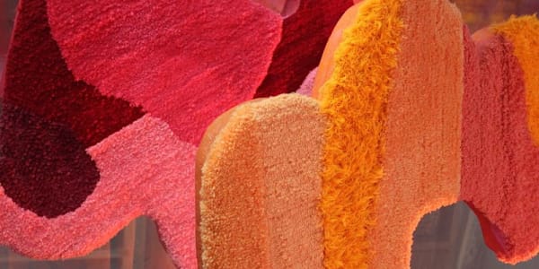 Orange and red, unevenly rounded, carpet style textile hung vertically